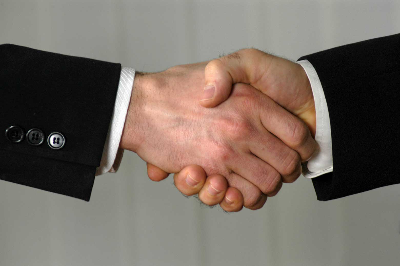 Poslovno sodelovanje 6139 Stisk roke med poslovnima partnerjema v elegantnih črnih oblačilih.